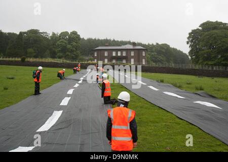 20 attivisti vestito in roadbuilders' alta viz capi di abbigliamento e copricapi rigidi roll out di un fake road nel campo immediatamente al di sotto della Rupe Hall, Cheshire in chi sta sostenendo il Cancelliere dello scacchiere George Osbornes ha una residenza . La protesta è stata fatta per evidenziare l'atteso rilascio di denaro per regimi roadbuilding in tutto il Regno Unito nella spesa imminente esaminare mercoledì 26 giugno Foto Stock