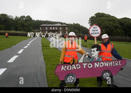 20 attivisti vestito in roadbuilders' alta viz capi di abbigliamento e copricapi rigidi roll out di un fake road nel campo immediatamente al di sotto della Rupe Hall, Cheshire in chi sta sostenendo il Cancelliere dello scacchiere George Osbornes ha una residenza . La protesta è stata fatta per evidenziare l'atteso rilascio di denaro per regimi roadbuilding in tutto il Regno Unito nella spesa imminente esaminare mercoledì 26 giugno Foto Stock