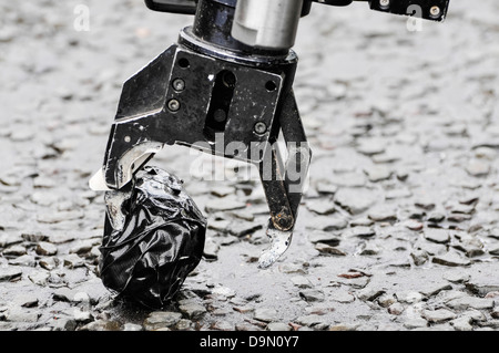 Pinza di presa di un esercito bomb disposal robot preleva un oggetto sospetto avvolto nel nastro Foto Stock