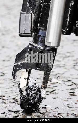 Pinza di presa di un esercito bomb disposal robot preleva un oggetto sospetto avvolto nel nastro Foto Stock