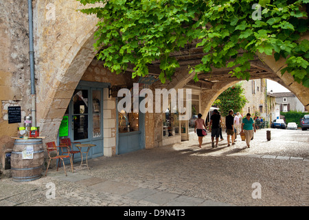 Uno dei molti archi con negozi e caffetterie nei dintorni di Place des Cornieres in Monpazier, Dordogne, Francia Foto Stock