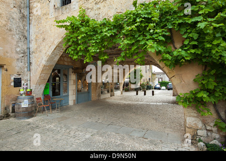 Uno dei molti archi con negozi e caffetterie nei dintorni di Place des Cornieres in Monpazier, Dordogne, Francia Foto Stock