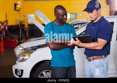 L'uomo africano all'interno del veicolo in officina con auto meccanico Foto Stock