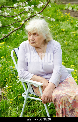 La nonna in giardino sotto una fioritura del melo Foto Stock