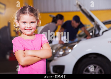 Carino bambina in attesa di madre in garage Foto Stock