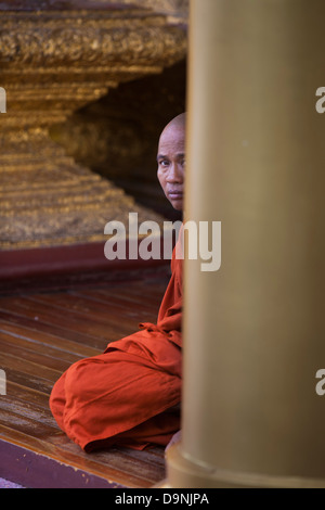 Un monaco buddista seduto sul pavimento alla Schwedagon, Birmania il tempio sacro nel cuore di Rangoon. Foto Stock