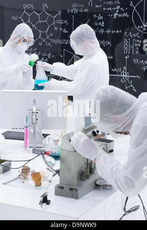 Close-up di due scienziati in un laboratorio di chimica di condurre un esperimento intorno ad una tabella lab con liquidi colorati, strumenti di laboratorio e m Foto Stock