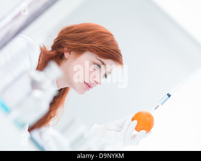 Close-up di donna in un laboratorio di analisi di un iniettato arancione Foto Stock