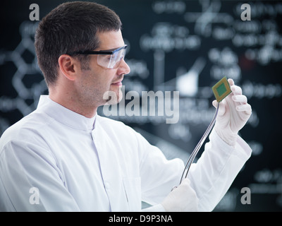 Close-up di scienziato in un laboratorio di chimica tenendo in mano e analisi di un disco rigido e una lavagna sullo sfondo Foto Stock