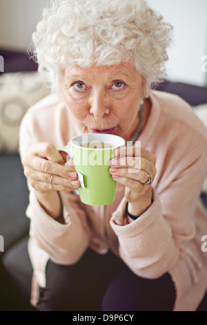 Primo piano di una matura lady guardando a voi mentre si beve il suo tè Foto Stock