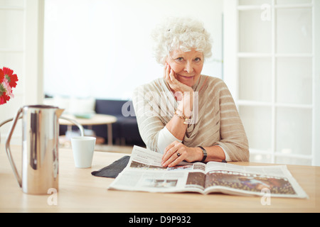 Ritratto di un elegante vecchia donna a casa leggendo una rivista Foto Stock