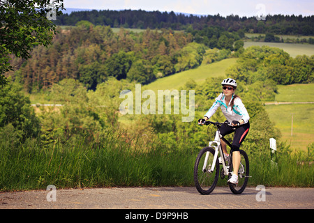 Una donna in bicicletta nella parte anteriore del paesaggio rurale Foto Stock