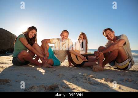 Gruppo di amici seduti sulla spiaggia Foto Stock