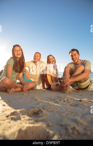 Amici sorridente seduto sulla spiaggia Foto Stock