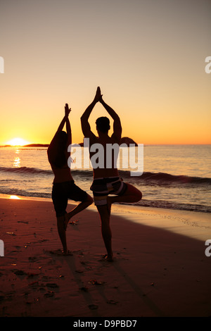 Sagome di persone facendo yoga sotto il tramonto Foto Stock