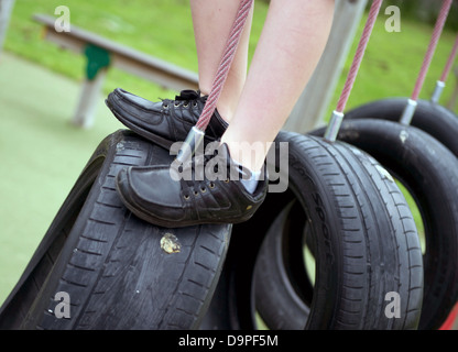 Regno Unito la scuola primaria ragazzo giocando su un pneumatico appeso nel parco giochi Foto Stock