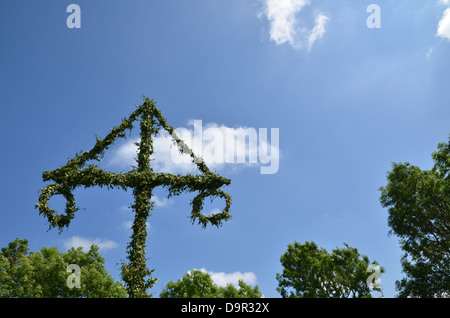 Midsummer pole al verde degli alberi e il cielo blu con nuvole bianche. Foto Stock