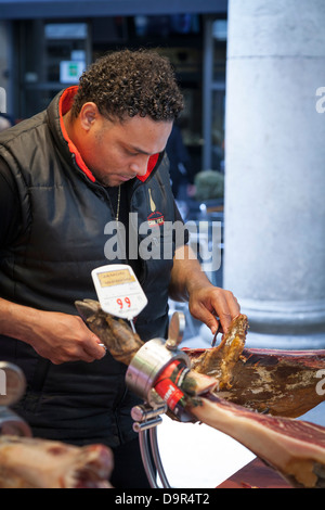 Commerciante fetta di taglio delle fette sottili di prosciutto iberico off prosciutto intero Foto Stock