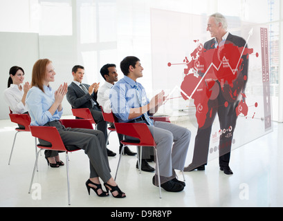La gente di affari battimani stakeholder in piedi di fronte a red mappa interfaccia schema Foto Stock
