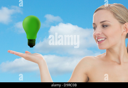 Donna sorridente guardando verde lampadina luce Foto Stock