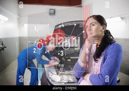 Auto meccanico con un cliente in cerca di interfaccia futuristica Foto Stock