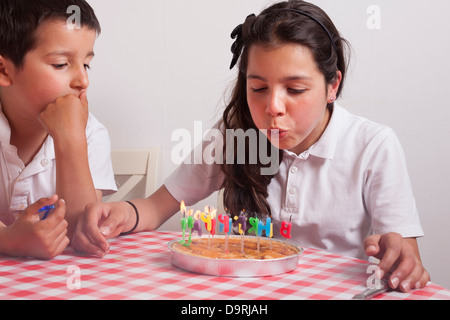 Giovane ragazza soffia-out candele su una torta di compleanno Foto Stock