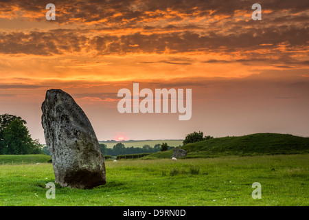Il sole tramonta dietro uno dei giganti di pietre Sarsen ad Avebury nel Wiltshire su una serata in giugno. Foto Stock