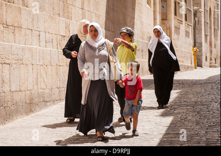 Israele Gerusalemme la città vecchia strada tipica scena 3 tre donne arabe white hijab hijabs abaya burka burkas camminando strada stretta boy & tourist chiede modo Foto Stock