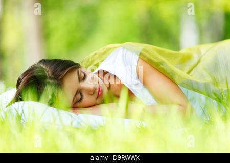 Giovane donna che dorme sul morbido cuscino in fresco di erba di primavera Foto Stock