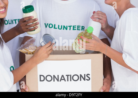 I volontari di mettere il cibo in scatola di donazione Foto Stock