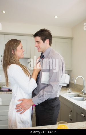 Donna che fissa il tirante del marito prima di lavorare Foto Stock
