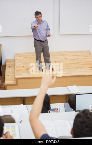 Studente in un aula magna a mettere mano fino Foto Stock