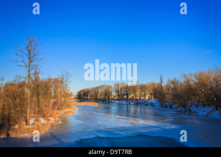 Inverno Fiume con ghiaccio su una superficie e nevoso costa sotto il blu cielo chiaro Foto Stock