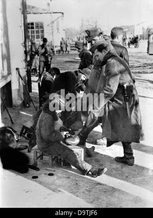 Testo di propaganda del socialista nazionale reporting sul retro dell'immagine. 'Prima di tutto a liberarsi della sporcizia della parte anteriore sulle scarpe. Non appena il tedesco mountain trooper arriva in un villaggio caucasico, egli prende le sue scarpe lucidati con un ragazzo di lucidatura scarpe.' motivo dal fronte orientale/Caucaso dal 8 di gennaio del 1943. L'attacco del Reich tedesco in Unione Sovietica è stato deciso nel luglio 1940 ed è stato preparato sotto lo pseudonimo di "Operazione Barbarossa' dal dicembre 1940. Il 22 di Giugno di 1941, il tedesco della Wehrmacht attaccato l'Unione Sovietica e ha iniziato la guerra German-Soviet. Foto Stock