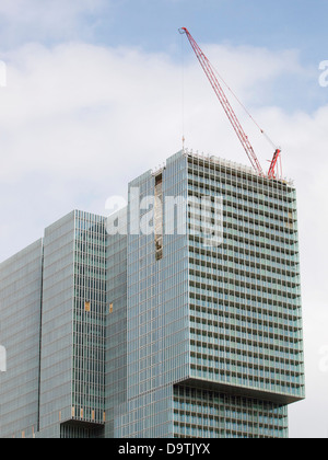 Quasi finito alto edificio di uffici a Rotterdam, Paesi Bassi, con una gru sul tetto. Foto Stock