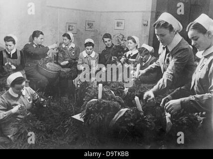 I soldati della Wehrmacht tedesca e le infermiere della Croce Rossa sono raffigurati durante i preparativi natalizi in un ospedale militare sul fronte orientale il Natale 1942. Luogo sconosciuto. La Propaganda nazista! Sul retro dell'immagine è datato 12 dicembre 1942: 'La Croce Rossa cura i lavori di decorazione natalizia in un ospedale militare nel nord del fronte Orientale. Diversi feriti, che si sono guariti, aiutano a legare corone di Natale che decoreranno le camere dell'ospedale con gusto." Fotoarchiv für Zeitgeschichte Foto Stock