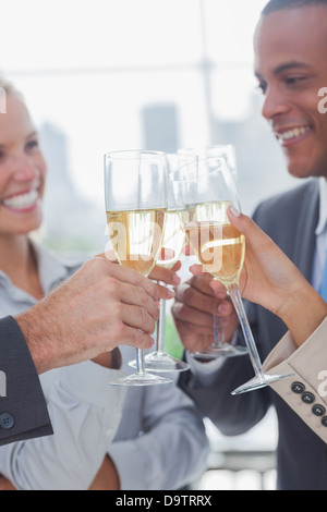 Il team di Business celebrando con champagne e bicchieri tintinnanti Foto Stock