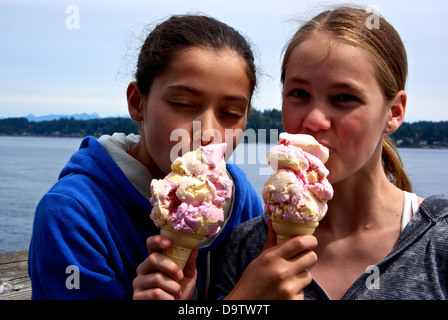 Due ragazze giovani degustazione reciprocamente le enormi coni gelato Campbell River BC Canada Discovery molo di pesca Foto Stock