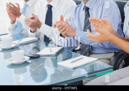 Un gruppo di uomini di affari che applaude in sala riunioni Foto Stock