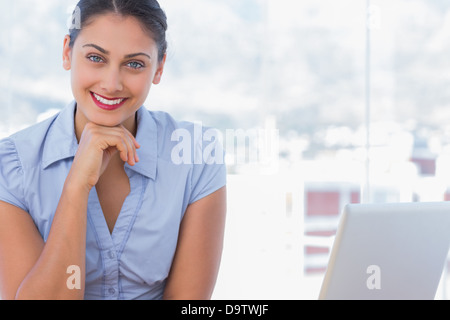 Felice imprenditrice seduto alla sua scrivania Foto Stock