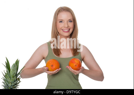 Sorridente giovane donna trattiene le arance di fronte a lei - concetto umoristico, isolato su bianco Foto Stock