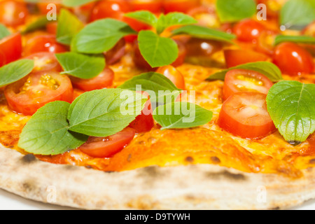 Pizza con pomodori ciliegia e le foglie di basilico. Foto Stock