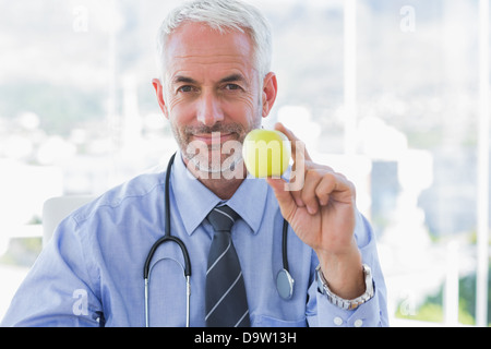 Medico in possesso di un Apple nella sua mano Foto Stock