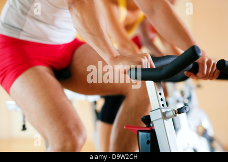 Tre persone la filatura in palestra, esercita per le loro gambe e cardio-training, solo gli arti e le ruote per essere visto Foto Stock