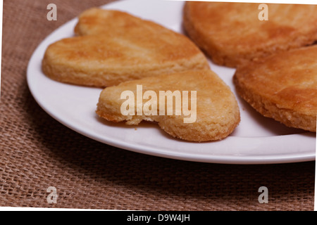 A forma di cuore i cookie su un piatto bianco. closeup Foto Stock