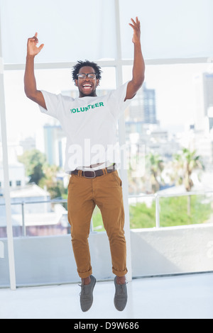 L'uomo jumping con volontario tshirt quindi solleva le braccia Foto Stock