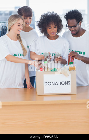 I volontari di mettere il cibo in scatola di donazione Foto Stock