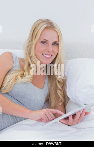 Donna di toccare il suo tablet a letto Foto Stock