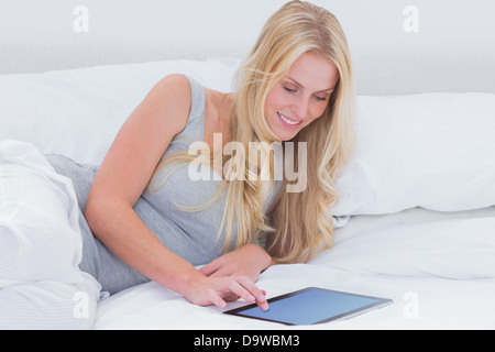 La donna nel suo letto toccando il suo tablet Foto Stock