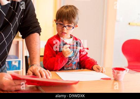 Ragazzo di 7 anni dow la sindrome educati in un IME qui intervento educativo educatore monitor Medical-Educational Institute Foto Stock